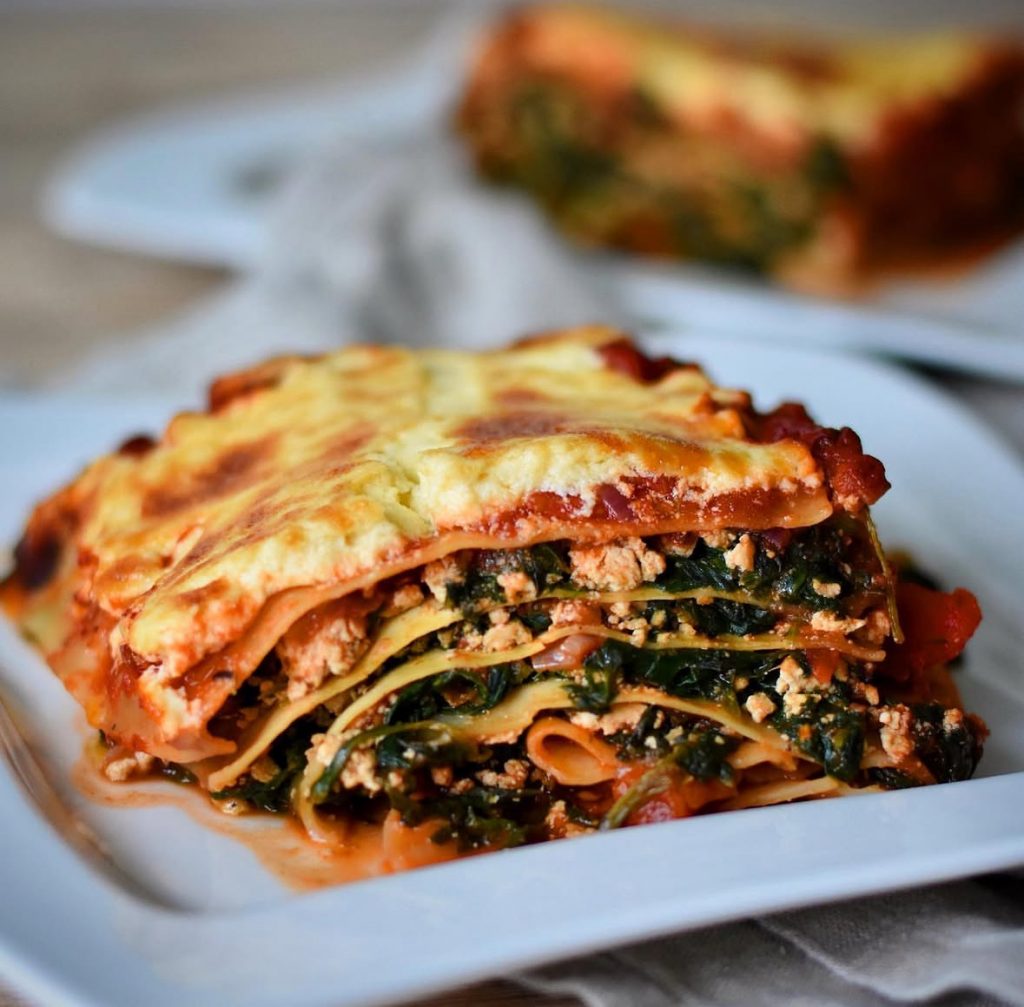 vegan spinach lasagna with tofu and a thick creamy béchamel topping arranged on a white plate