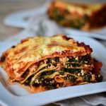 vegan spinach lasagna with tofu and a thick creamy béchamel topping arranged on a white plate