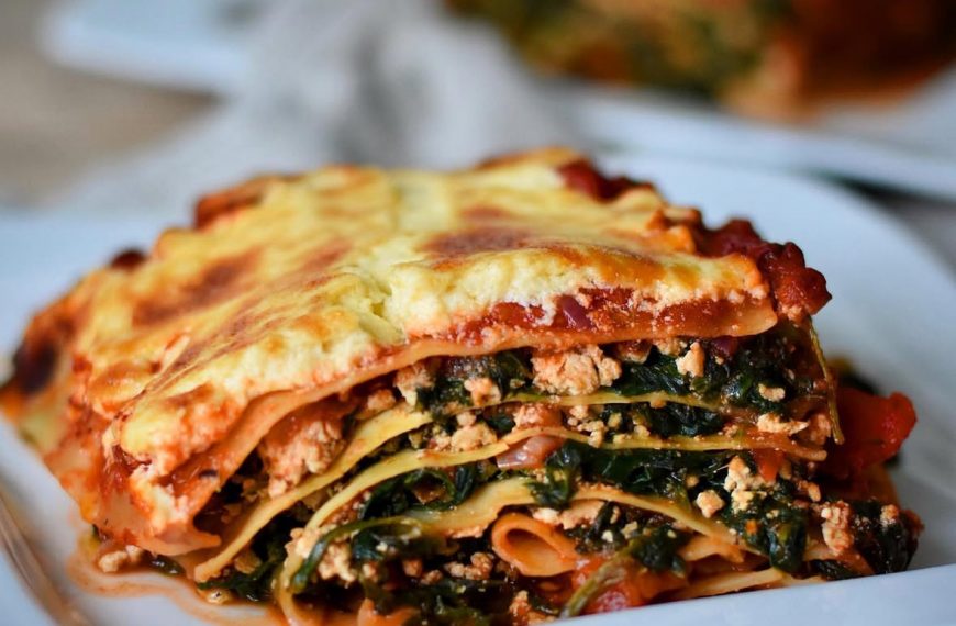 vegan spinach lasagna with tofu and a thick creamy béchamel topping arranged on a white plate