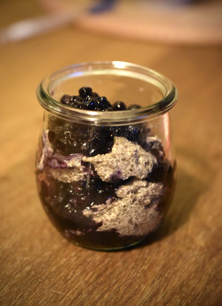 Cashew Chia Pudding in a small glass layered with wild blueberries