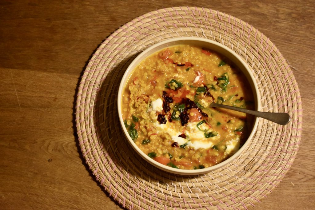 a plate of vegan red lentil dal on a wooden table