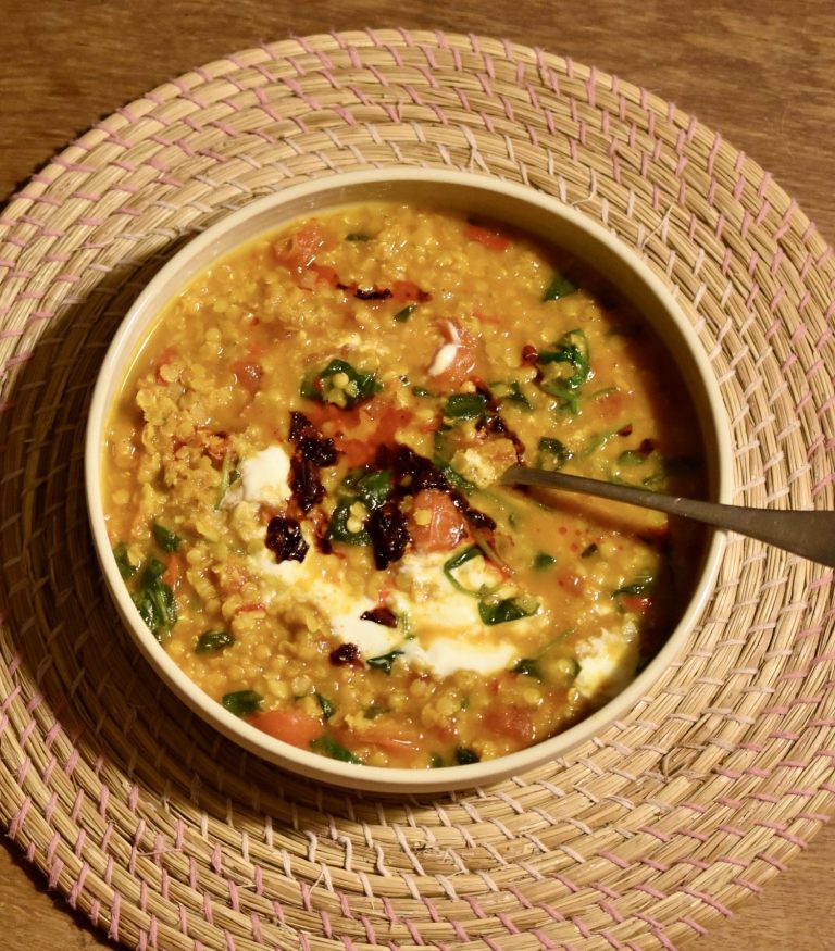 a plate of vegan red lentil dal on a wooden table