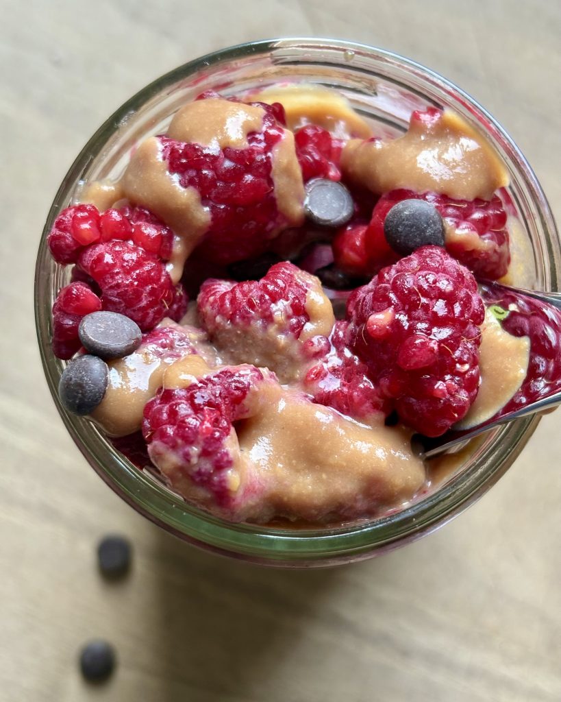 blended chocolate chia pudding parfait with raspberries and peanut butter caramel topped with choc chips