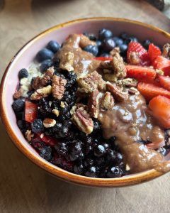 a bowl of vegan oatmeal with berries, almond butter, and pecans