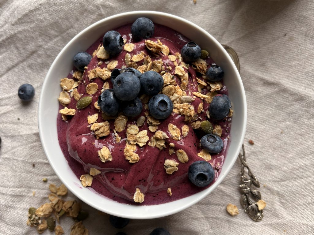blueberry nice cream in a small bowl with granola and fresh blueberries