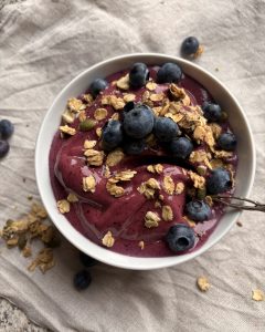 blueberry nice cream in a bowl with blueberries and granola