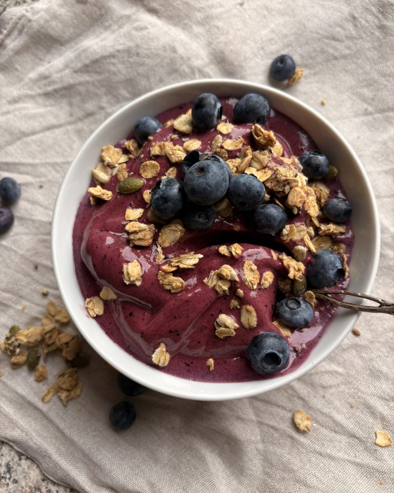 blueberry nice cream in a bowl with blueberries and granola