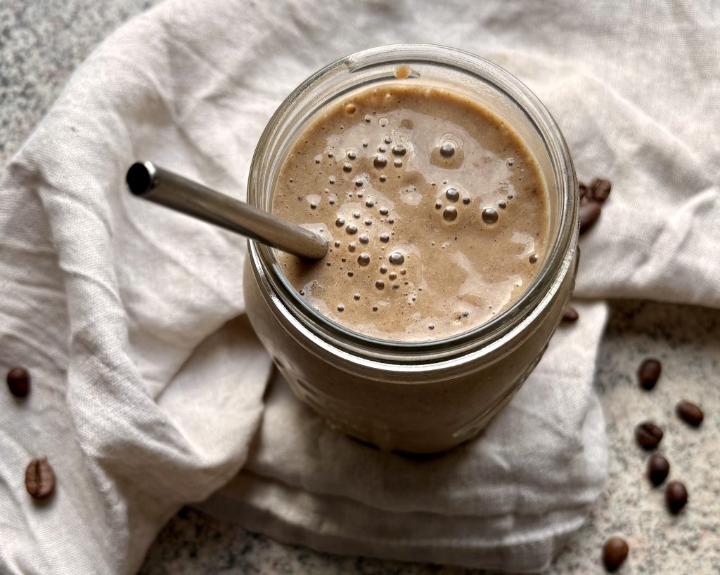 coffee smoothie in a glass with a glass straw and decorations