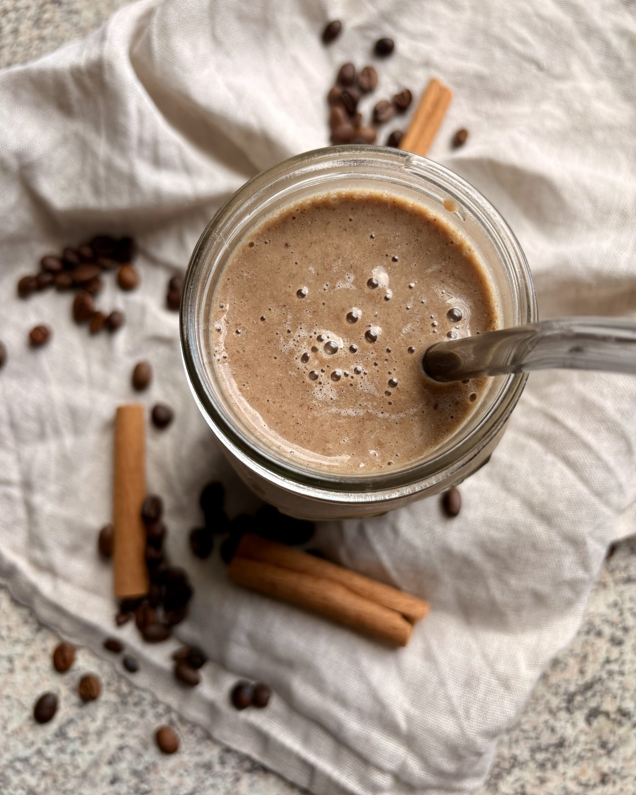 coffee smoothie in a glass with a glass straw and decorations