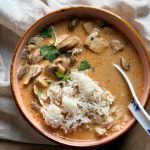 vegan tom yum soup with mushrooms and tofu in a bowl with a spoon