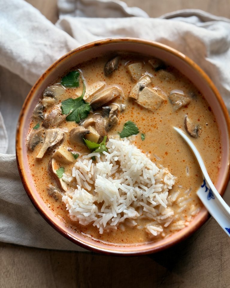 vegan tom yum soup with mushrooms and tofu in a bowl with a spoon